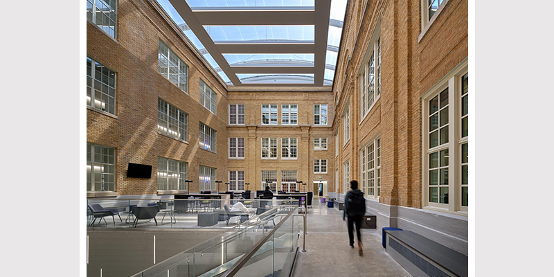 student strolls the inside of the large atrium surrounded by Ultra Series historic windows