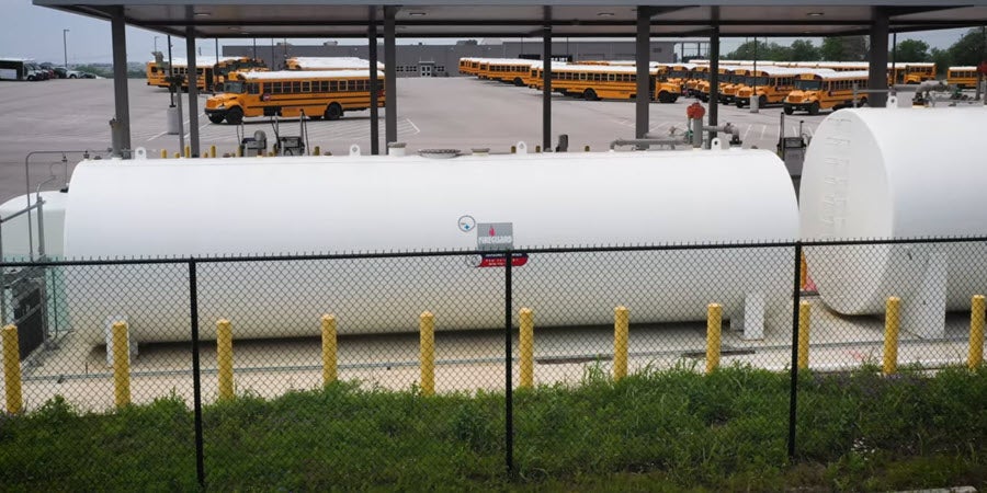 Fuel tanks with yellow school buses in the background.