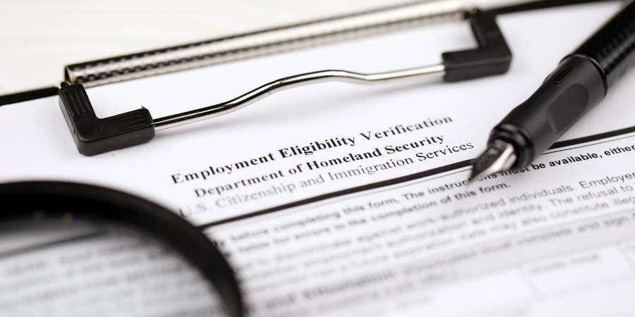 Image of an employment eligibility verification form and a black on a clipboard