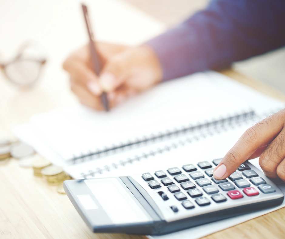 person using calculator and writing in notebook