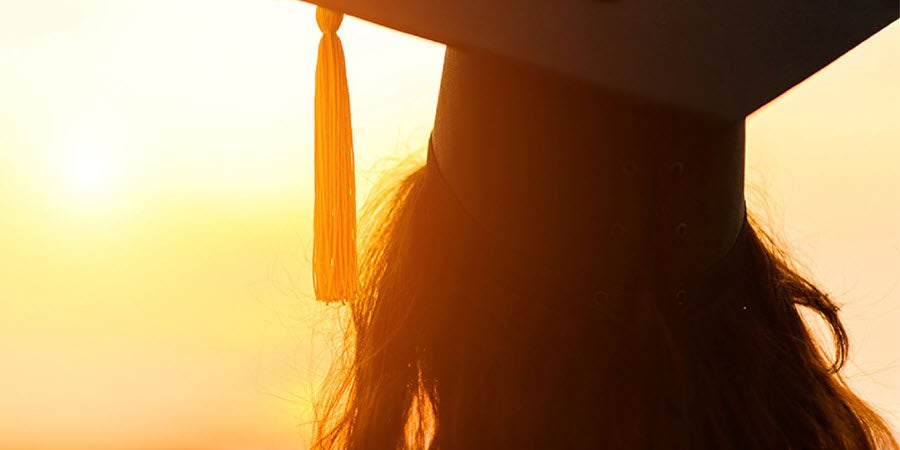 Girl wearing a graduation cap facing the sun
