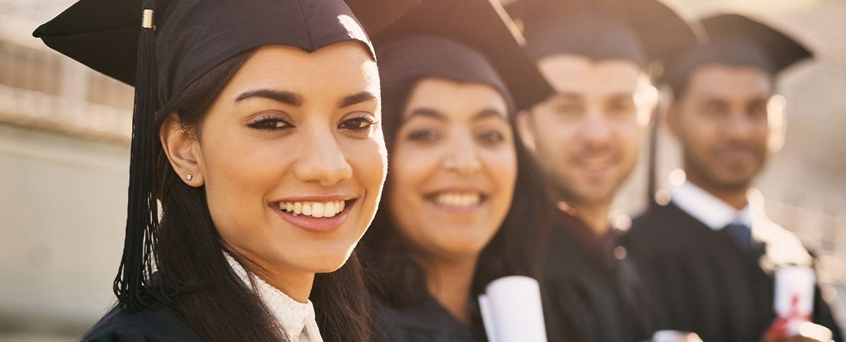 A woman and other students have graduated and they are in their caps and gowns with their diplomas.