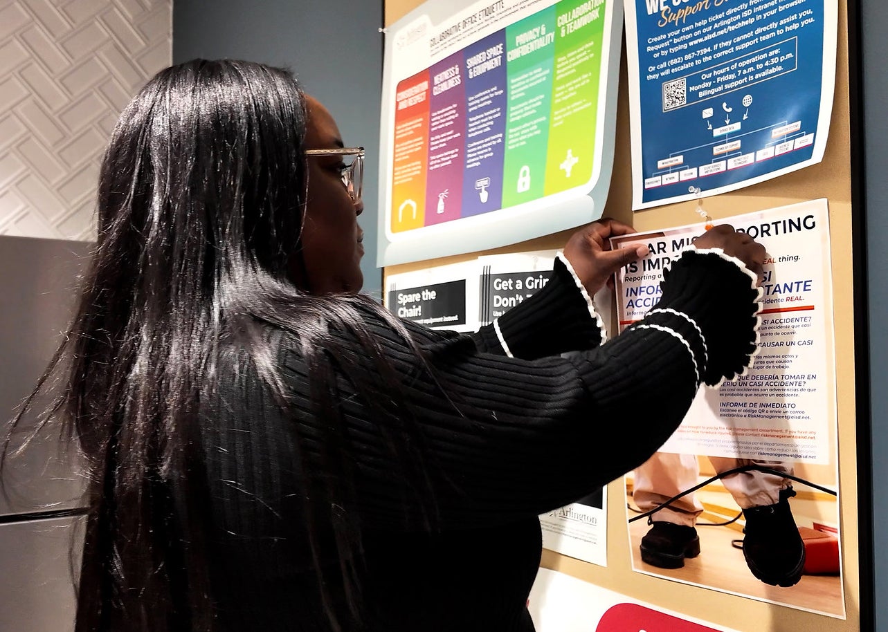 Arlington ISD’s Near-Miss Reporting Program aims to reduce workplace injuries. As part of the initiative, Jennifer Bakare-Brown — the district’s safety manager — helps place posters with a QR code linking to a simple form that makes it easier to report hazards that could cause injuries.