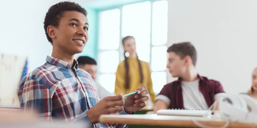 A boy holding a pen in a classroom setting