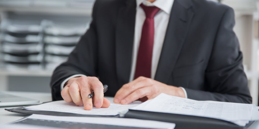 Man in suit reviewing paperwork with pen in hand