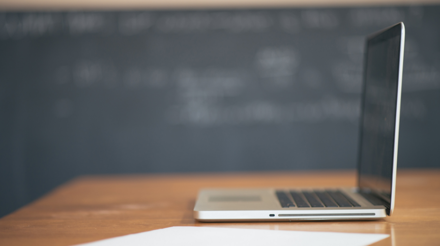 photo of an open laptop on a desk with a black chalkboard in the background