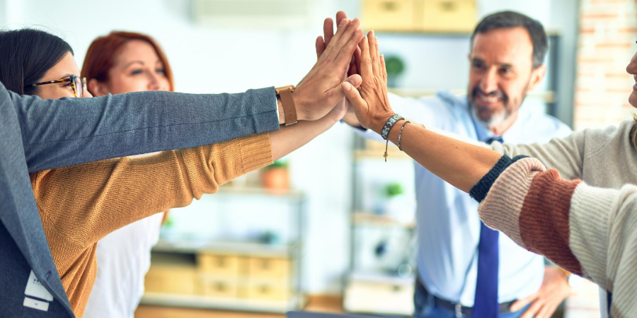 Group of men and women in professional attire giving each other a high five