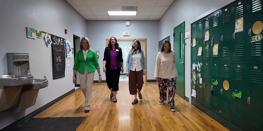 Amy Campbell from TASB HR Services with three other women walking in a school hallway.