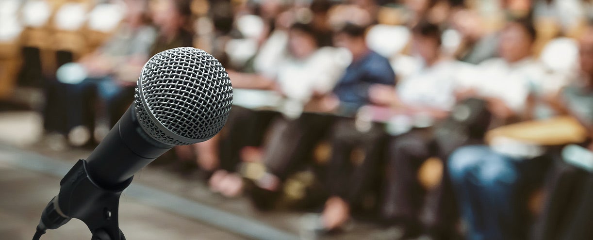 Up close of microphone with large crowd in background