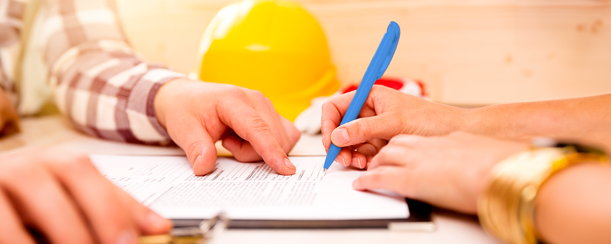photo of a person's hand holding a blue pen signing a contract (banner image)