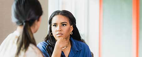Woman listens to another woman in a meeting