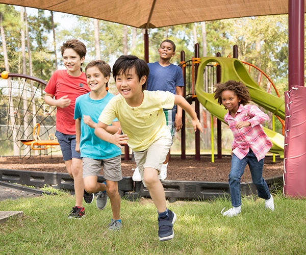 Multi-ethnic group of school children running on school playground
