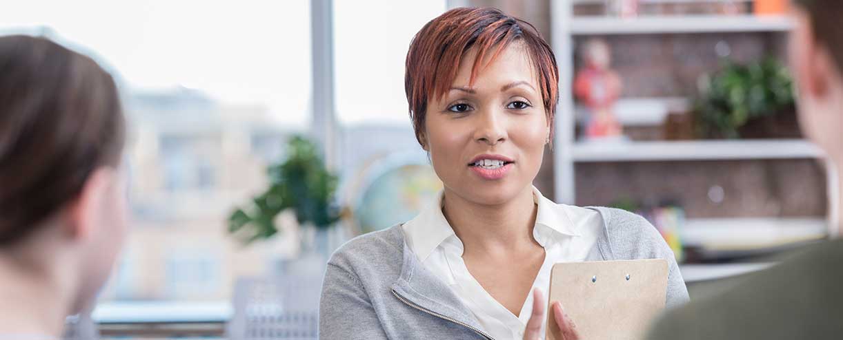 Woman with a clipboard talks to two people 