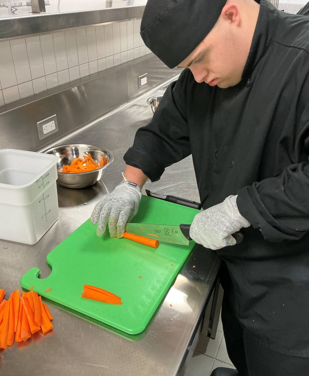 Lucas Baldwin slices carrots as part of his culinary skills training.