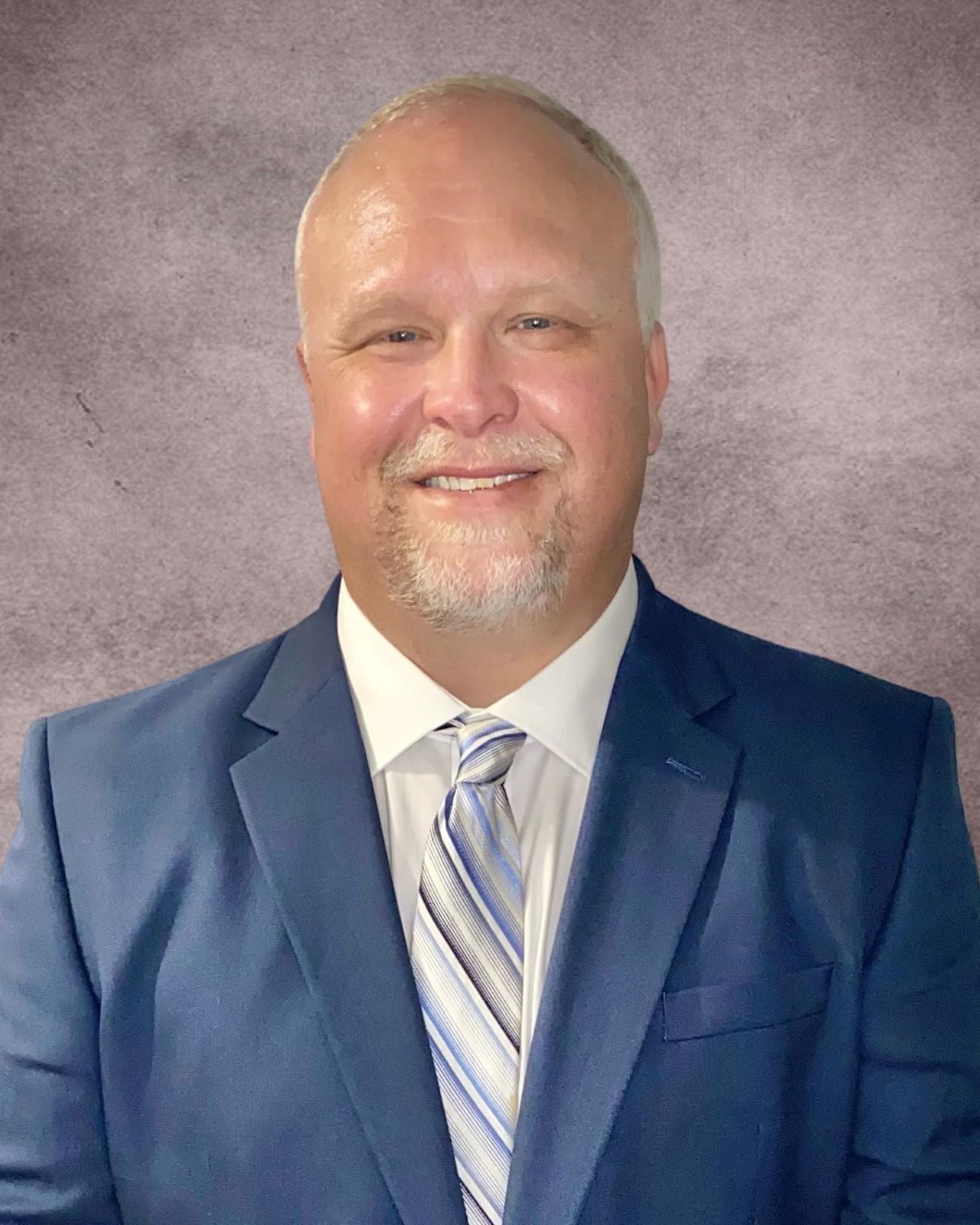 Professional headshot of William Scott Kilgore. Mr. Kilgore is wearing a white dress shirt with a blue and white tie, and a blue suit on top. 