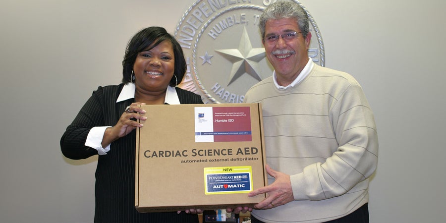 TASB Senior Marketing Consultant Rosa Brown presents an AED to school district representative
