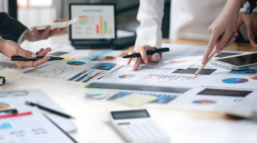 photo of people meeting at a table to analyze data on printed charts and graphs