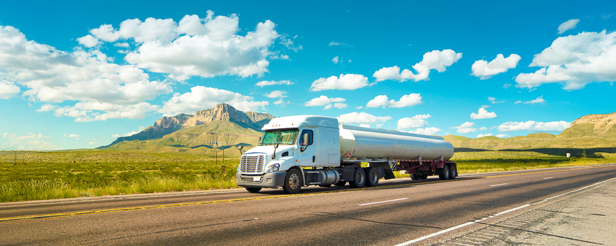 Fuel truck driving on a scenic highway with clear skies overhead