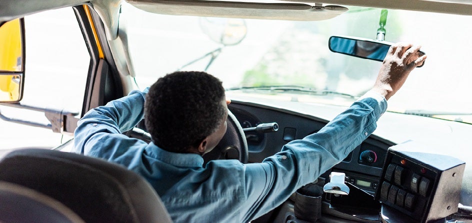 School bus driver checking rearview mirror