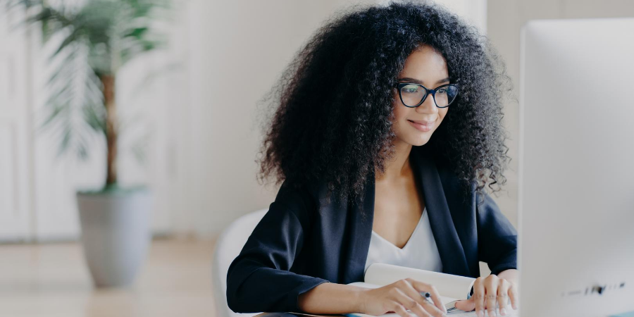 Young, Black female sitting and working at a desktop computer