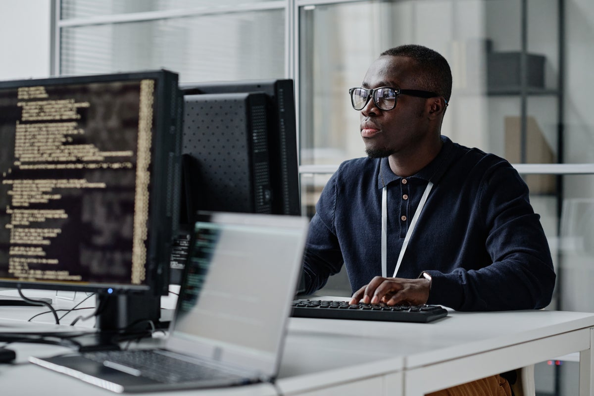 Image of a young man working on a computer in an office environment.