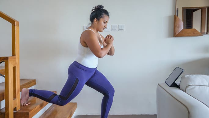 A woman is doing a lunge as part of her workout of the best full body exercises to do at home. 