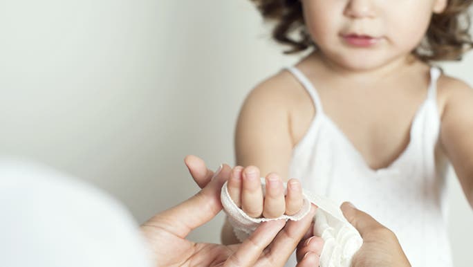Someone is bandaging a child’s hand.