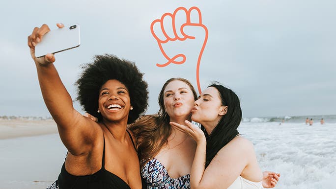 Three happy, confident female friends taking a selfie at the beach