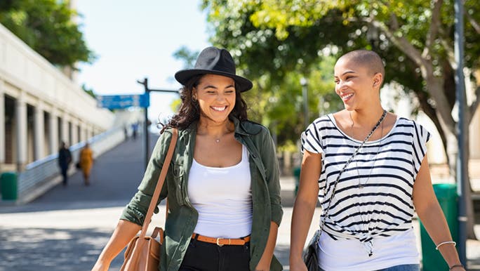 Two women walk together on a quiet street, they may be walking to stay at a healthy weight. 