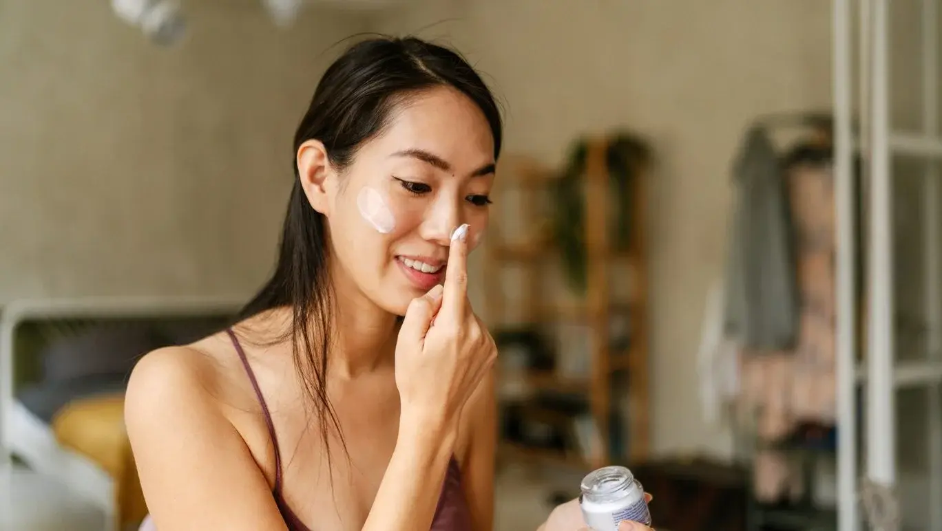 Woman applying a facial moisturiser