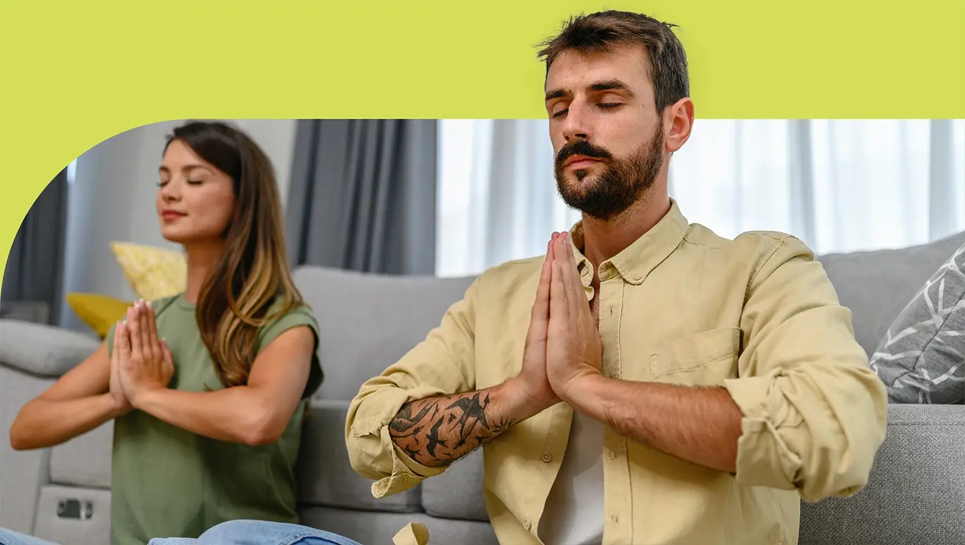 couple sitting together meditating with hands together