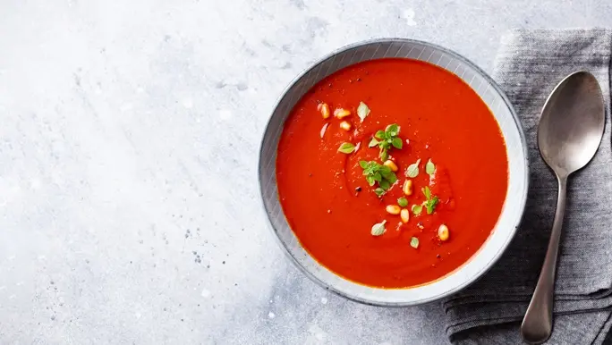 Roasted tomato soup in a bowl with a napkin and spoon