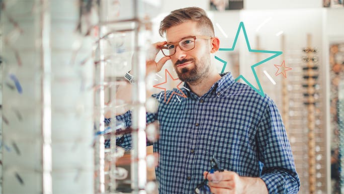 Young man trying on glasses at the optometrists 