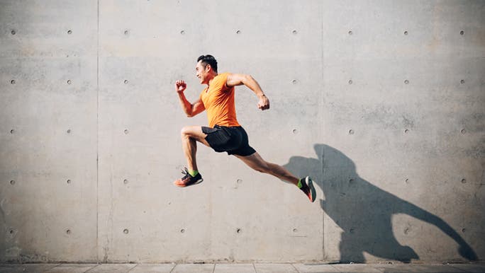 Man jumping in a running post in front of a concrete wall, he is at risk of getting a common sports knee injury. 