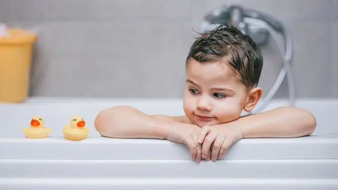 Boy in a bathtub with two rubber ducks