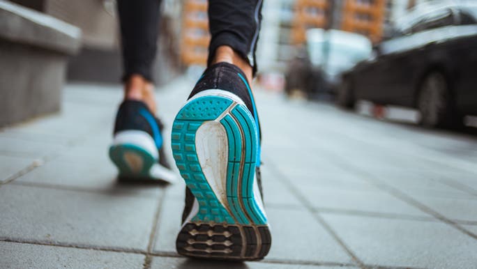 A close up of a blue sneaker in action, the owner is enjoying a morning walk through the city.