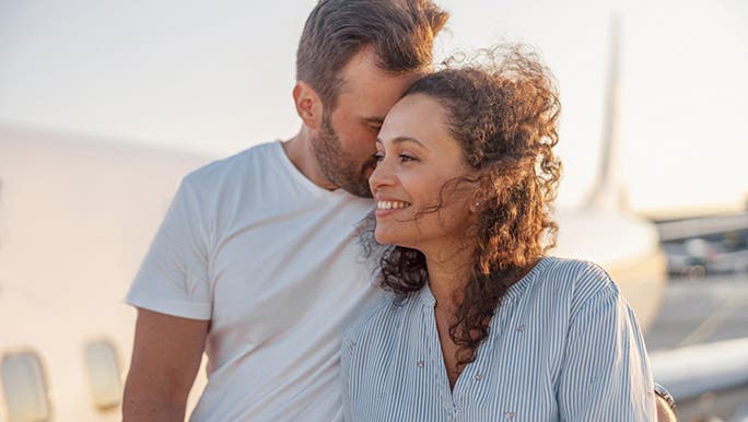 A white Caucasian man wearing a white T-shirt has his arm around a woman with brown curly hair and a blue shirt as they possibly discuss how to increase fertility
