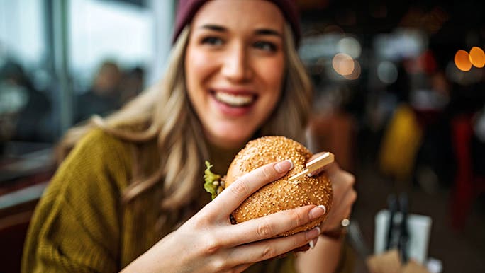 A woman is at a restaurant about to eat a hamburger roll and is wondering how a gluten-free diet impacts the immune system