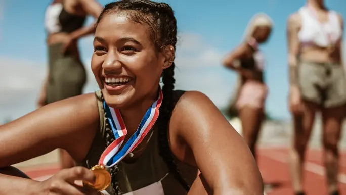 Happy young woman smiling and recovering after a running race