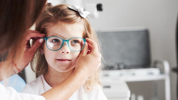A child is being fitted with blue prescription glasses, she is too young for contact lenses. 