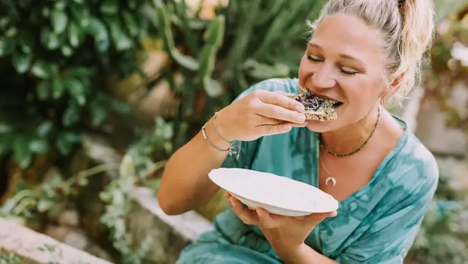 Young blonde woman eating a vegan sandwich for lunch in the garden