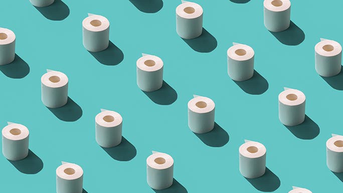 On a blue background, lots of rolls of toilet paper are lined up like soldiers. 