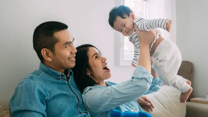 Mum and dad at home playing with their son