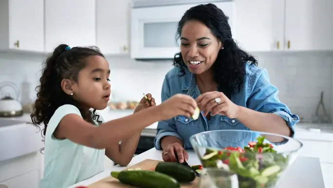A woman and her daughter preparing a healthy meal at home