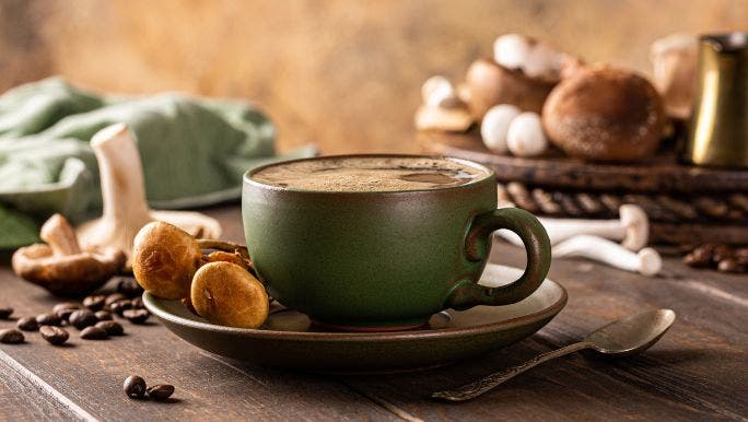 Mushroom coffee in a green mug with mushrooms displayed on table 