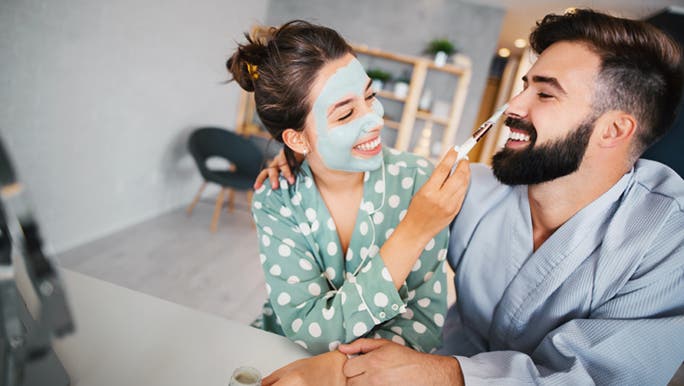 A young couple in their pajamas apply face masks and beauty products together, including the best collagen powder.