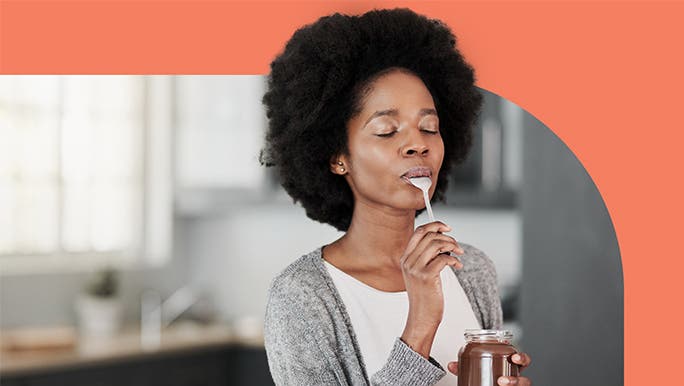 Young woman savouring the taste of chocolate spread she is eating with a spoon out of the jar.