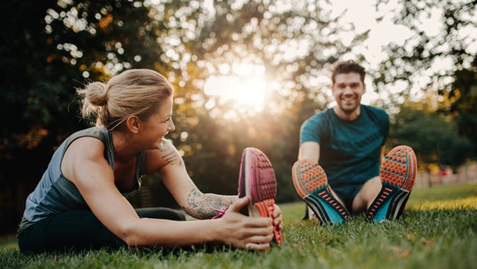 A young couple in a park stretching knows why flexibility is important.