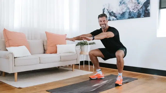 Personal Trainer Sam Wood doing a squat exercise indoors