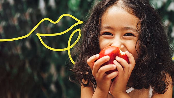 Happy girl smiling and eating a red apple